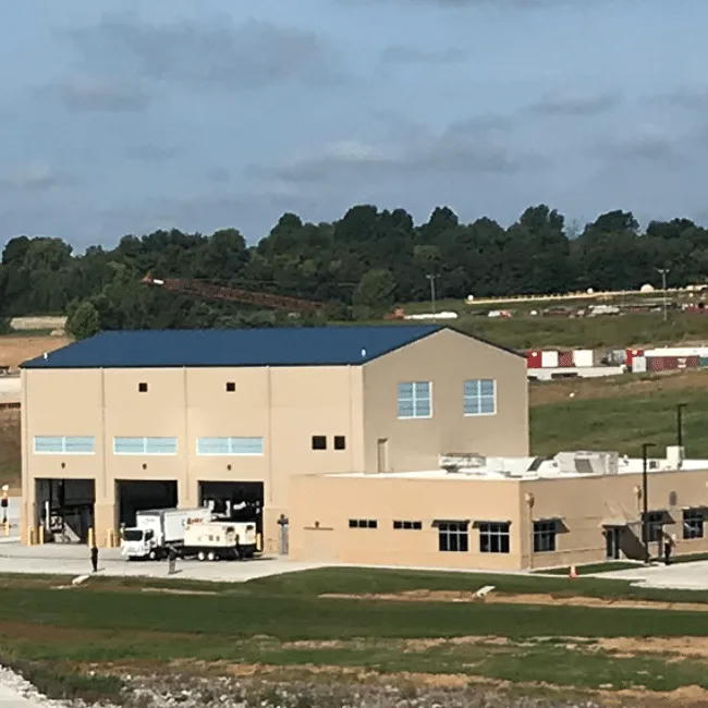 Vehicle maintenance facility with three drive-in service bays and a blue standing-seam roof