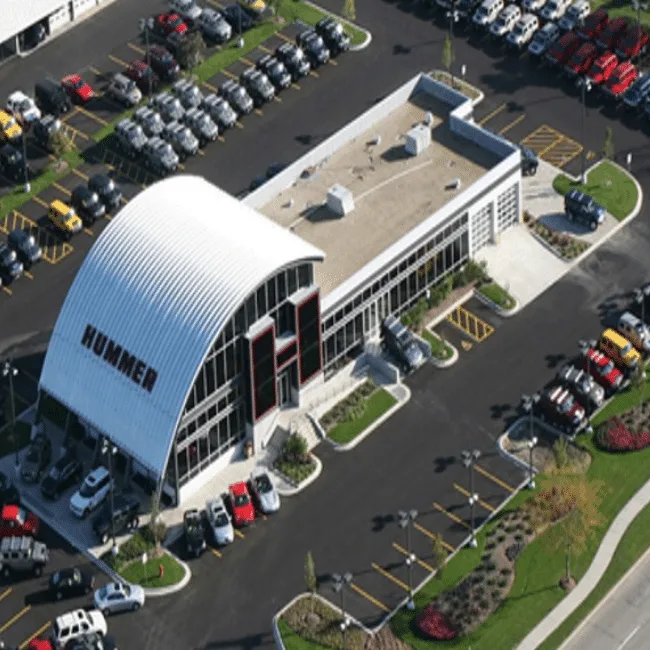 Aerial view of a Hummer dealership with a curved standing-seam metal showroom roof and a full vehicle lot