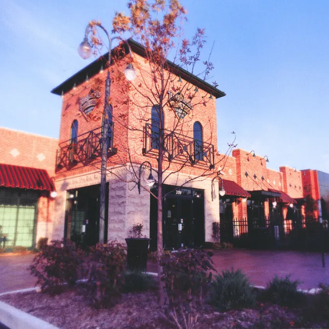 Restaurant renovation and expansion with a brick tower entry, illuminated at dusk after an interior finish-out, McHenry, IL