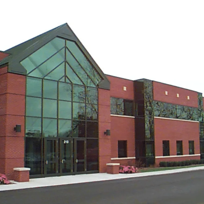Two-story brick office building with a peaked glass entry atrium and stone accent panels