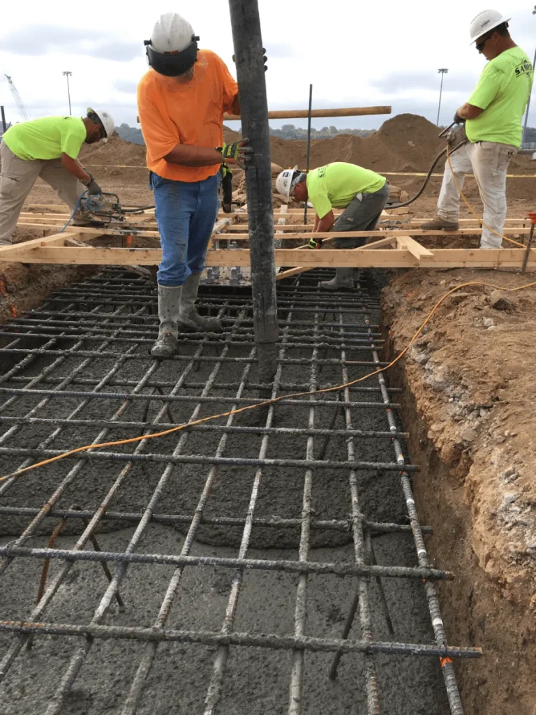 Crew tying rebar and setting forms for a new building foundation, supporting the next phase of structural construction.