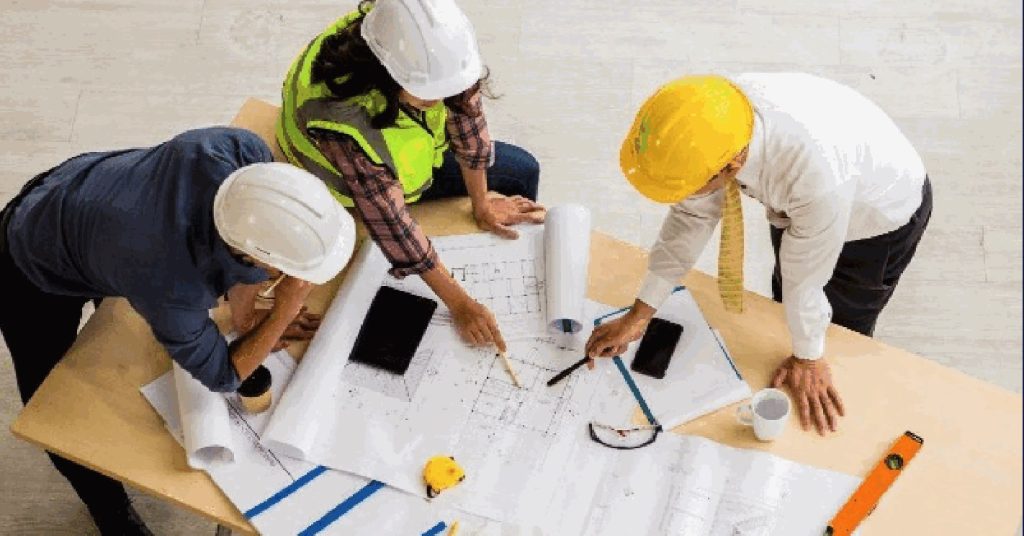 Contractors in hard hats reviewing drawings around a table on site