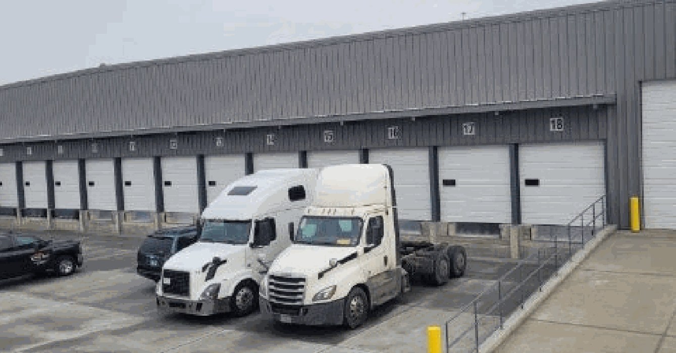 Semi truck at the loading docks of a completed warehouse with offices and truck bays