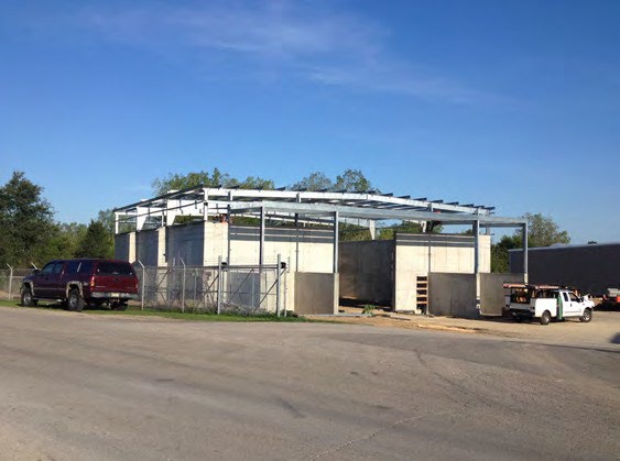 Steel frame of a transportation facility under construction with vehicles parked alongside in Woodstock, Illinois