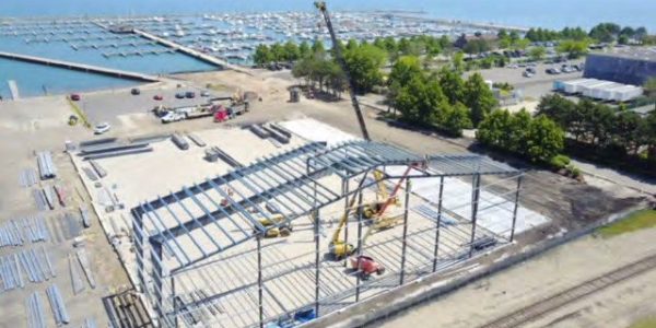 Aerial view of the steel frame of a boat sales and storage facility under construction beside a marina