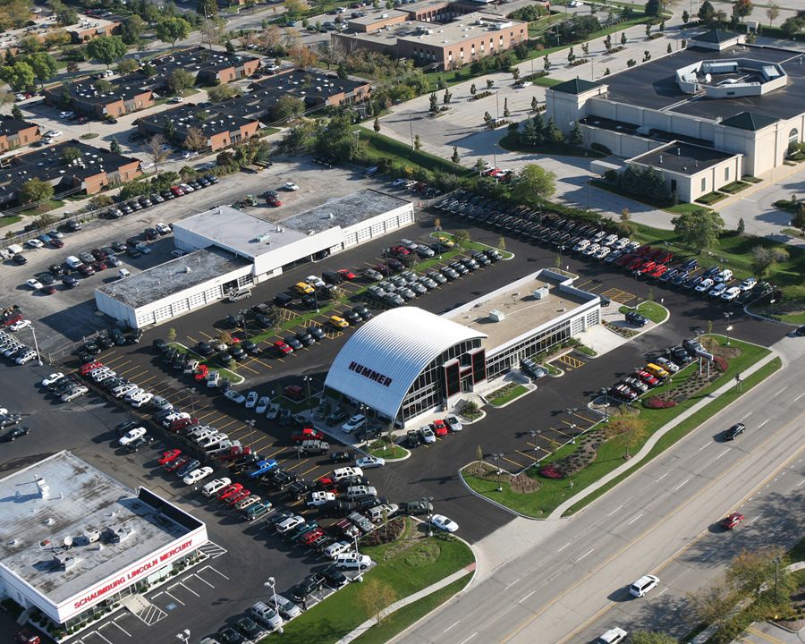 Aerial view of a car dealership with an arched showroom roof and a full vehicle lot in Schaumburg, Illinois
