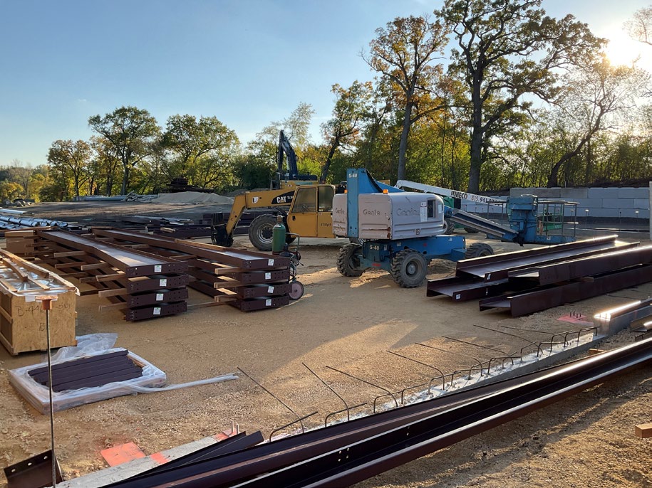 Stacked steel framing and a telehandler on the concrete slab of a building under construction in Island Lake, Illinois