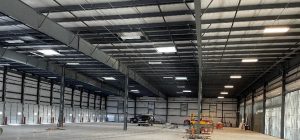 Interior of a completed steel building with exposed structural framing and overhead lighting