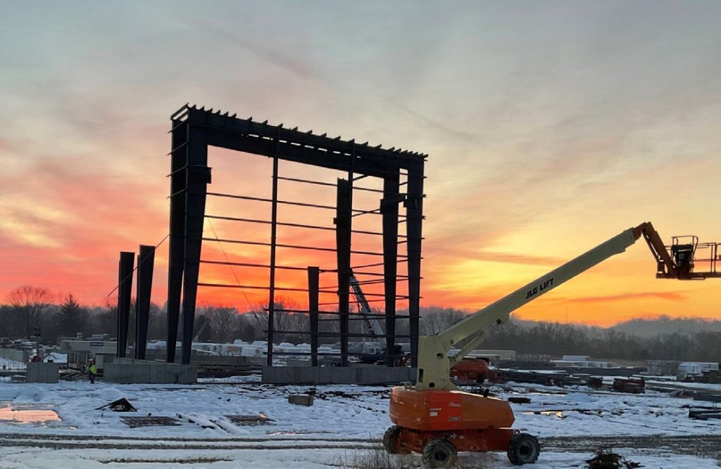 Steel frame of a manufacturing addition at sunset with a lift working alongside it in Hamilton County, Ohio