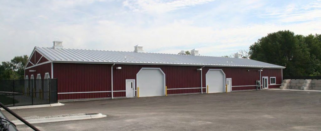 Red metal maintenance building with four white overhead doors in Waukegan, Illinois